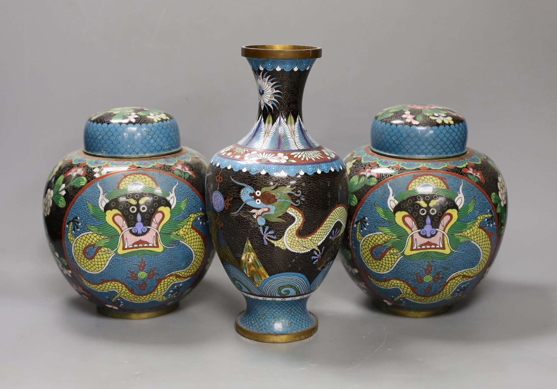 A pair of early 20th century Chinese cloisonné enamel ‘dragon’ jars and covers and a similar vase. Tallest 25.5cm